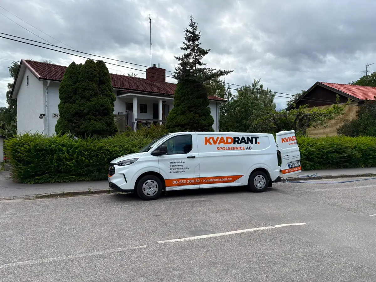 Kvadrants spolbil på gatan utanför en villa med spolslangen utrullad vid stopp i toaletten