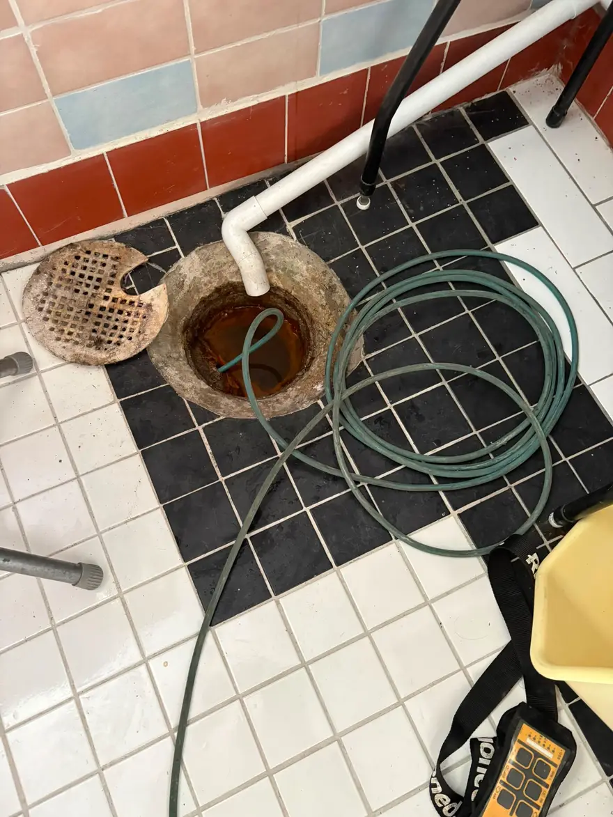 Spolslang nedförd i en äldre gjutjärnsbrunn i en tvättstuga vid avloppsspolning i Nynäshamn
